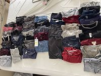Top down view of 39 men's t-shirts laid out on a bed showing assorted colors, brands, and styles.