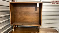 Front view of mid century style wooden bookcase showing interior and four legs.