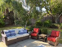 Overall view of the patio set including sofa, two chairs, and end table in backyard