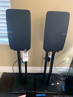 Front view of two Sonos Play:5 speakers on StudioTech stands against wall