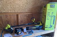 Full kit on shelf showing string trimmer/edger, blower, battery, charger, spools, manual, and product box.