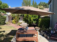 Full setup: table with umbrella in place and two benches on concrete pad in backyard