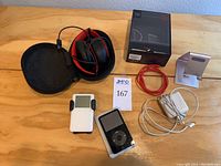 Top down view of all items on table including two iPods, BeatsX headphones in case with cables and box, two iPod stands, charger cable and adapter.