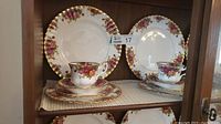 Two full place settings each containing a dinner plate, salad plate, side plate, saucer, and cup with floral and gold trim design.