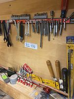 Photo showing an assortment of small tools including Irwin drill bits, screwdriver bit ends, wrenches, and fine tip woodworking tools arranged on and below an orange magnetic tool holder strip.