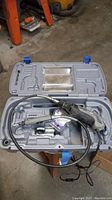 Open gray plastic carrying case containing Dremel 400 XPR rotary tool with attached flexible shaft and accessories inside molded slots