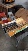 Wide view of four drill bit cases placed on a table showing variety and assortment in sizes and types