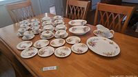 Full set on table showing dinner plates, salad plates, side plates, teacups with saucers, bowls with drip plates, vegetable bowls and platter