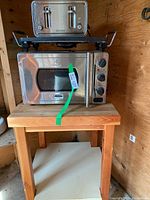 Wolfgang Quick kitchen oven and Black and Decker toaster stacked on butcher block table in wood shed