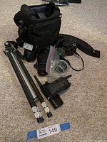 Overview of kit spread on carpet showing camera bag, external flash, lenses, tripod, hand grip, strap and accessory bag