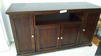 Front view of espresso TV console showing four closed doors and open center shelf