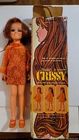 Crissy doll standing next to original box displaying front artwork and photos