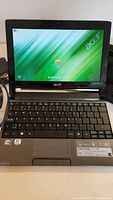 Front view of open Acer Aspire One 533 laptop powered on showing Windows 7 login screen.