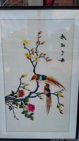Full view of framed silk embroidery showing two colorful birds on a blooming branch with Chinese characters.