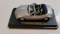 Diecast model of 1996 BMW M Roadster silver color from side angle showing seats and dashboard on black display base.