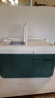 Front view of green and white Coleman cooler with closed lids.