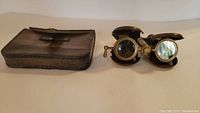 Image showing the opera binoculars unfolded next to the leather case.