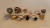 Photo showing all 11 rings arranged in a row, highlighting the different designs including gemstone rings, lion motif, floral clusters, and textured bands.