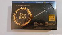 Front of the sealed box showing LOTR branding, sword replica and bonus offers sticker