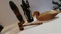 Full view of all items in the lot: wooden duck decoy, two wooden figurines, and Mason's gavel.