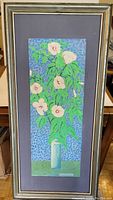 Full view of framed oil painting showing white flowers with green leaves in white vase on blue textured background.