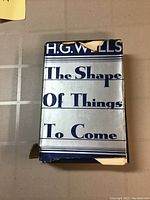 Front cover with dust jacket showing book title and author H.G. Wells. Dust jacket is worn with tears and missing pieces.