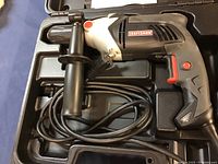 Photo of the Craftsman 1/2 inch drill lying inside its black carrying case showing the drill with side handle and power cord.