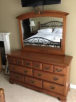 Front view of honey oak dresser with attached arched mirror against wall