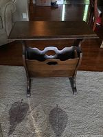 Front view of wooden magazine rack with table top showing curved side panels and open magazine storage compartment.