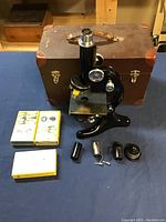 Overview of microscope, hard case, boxed slides, and lens accessories arranged on a surface.