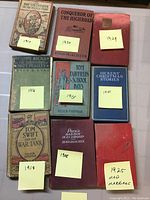 Photo showing 10 vintage books arranged flat with sticky notes indicating publication years from 1908 to 1946.