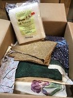 Box of assorted quilting fabrics and a bag of Warm & Natural cotton batting on top