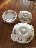 Photo shows six dessert plates stacked and two covered serving dishes with lids, all decorated in Royal Albert Lavender Rose floral pattern.