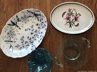 Photo showing large white ceramic platter with blue floral pattern, oval porcelain floral platter, textured blue glass bowl, and clear rectangular glass dish with handles.