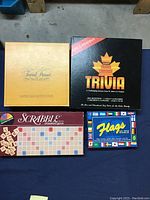Four board games laid out including Trivial Pursuit, Trans Canada Trivia, Flags of the World, and Scrabble