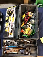 Top-down view of two plastic tool boxes filled with various hand tools and a micro tester kit. Tools are visibly used and include wrenches, ratchets, screwdrivers, drill bits, and other hardware.