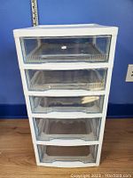 Front view of the 5 drawer plastic storage container showing clear drawer fronts and white frame.