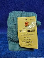 Folded blue-green kilt hose with original tag from Edgar of Scotland showing material composition and size Large.