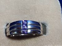 Front view of sterling silver ring showing three square amethyst center stones set vertically with additional crystal rhinestones on the band.