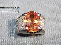 Front view of sterling silver ring with oval orange citrine center stone and clear crystal rhinestones on band