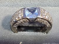 Close-up photo of the silver ring showing the pale blue center stone and clear crystal rhinestones on the band.