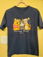 Full view of black vintage T-shirt featuring Winnie the Pooh, Eeyore, and Tigger with 'Group Hug!' and Disneyland text on front.