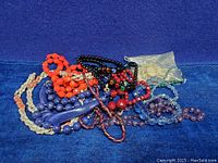 Mixed lot of various vintage bead necklaces including red, purple, blue, white beads and translucent beads with a bag of white carved pendants