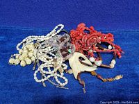 Top view of vintage mixed beads necklaces showing red coral beads, white beads, and carved bone pendant necklace