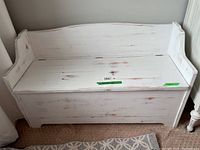 Front view of white wooden storage bench with weathered paint finish and flip-top seat.