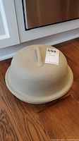Stone clay baker with domed cover on hardwood kitchen floor.