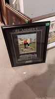 Framed picture with Jack Nicklaus at St. Andrew's resting on the floor, showing frame and overall item
