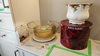 Royal Albert vase on original red rose decorated box beside four glass bowls, two showing chips, and KitchenAid produce preserver package.
