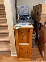 Front view of wood framed water cooler with plastic water jug and metal spigot.