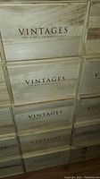 Stacked wooden wine boxes showing VINTAGES branding clearly on each box.